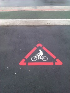 Warning stencilled at property exits to protect cyclists on cycle lane from leaving cars